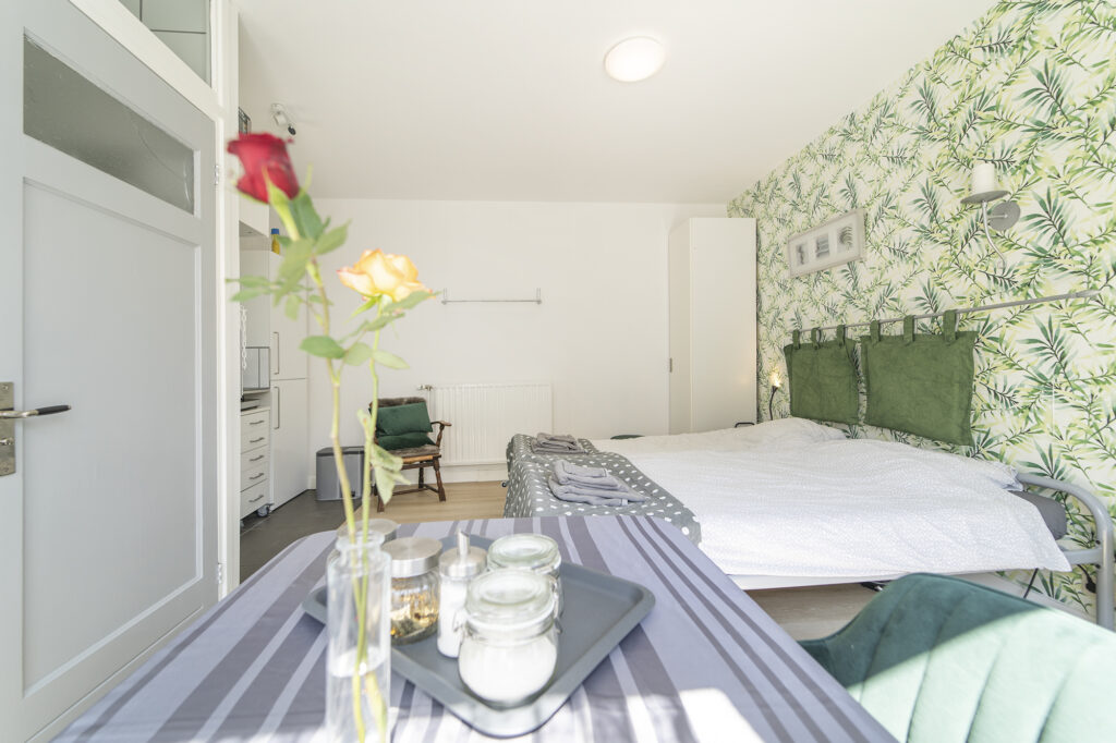 Slaapkamer met groen bladerbehang en rozen op tafel