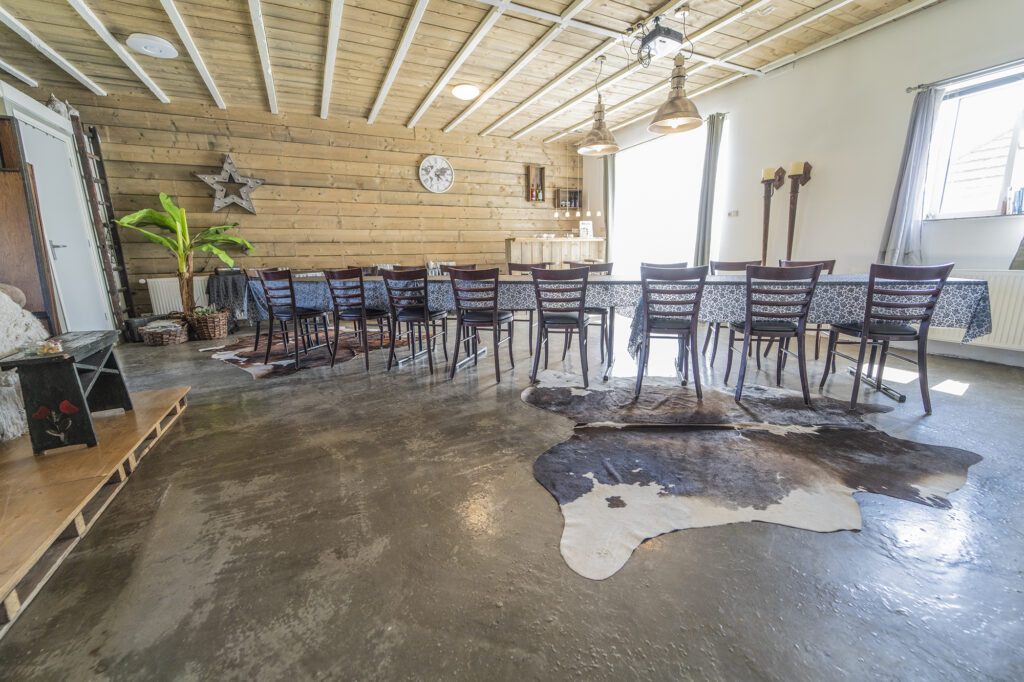 Graanloft met lange vergadertafel, houten wanden en koeienhuid op de vloer