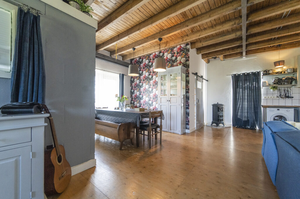 Ruime woonkamer in een loft met eettafel, gitaar en houten balken