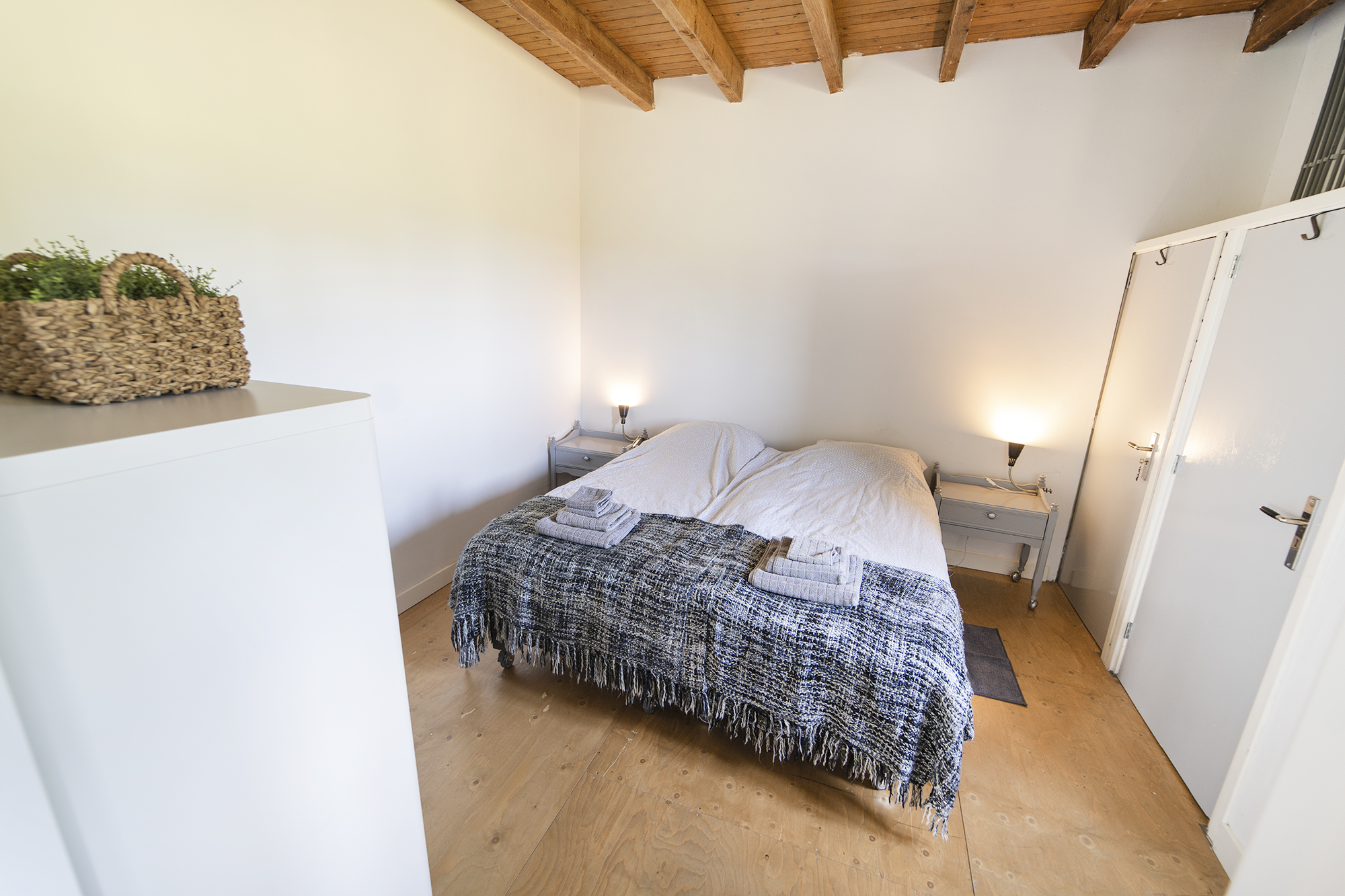 Slaapkamer met tweepersoonsbed, houten balken en houten vloer