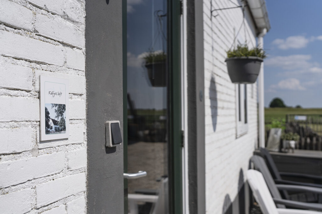 Eigen voordeur van een loft met plantenbak en terrasstoelen