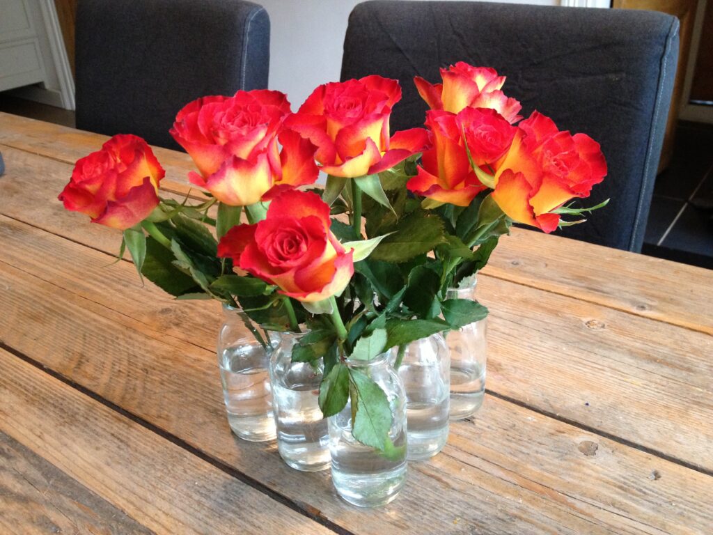 Rode rozen in glazen vaasjes op een houten tafel