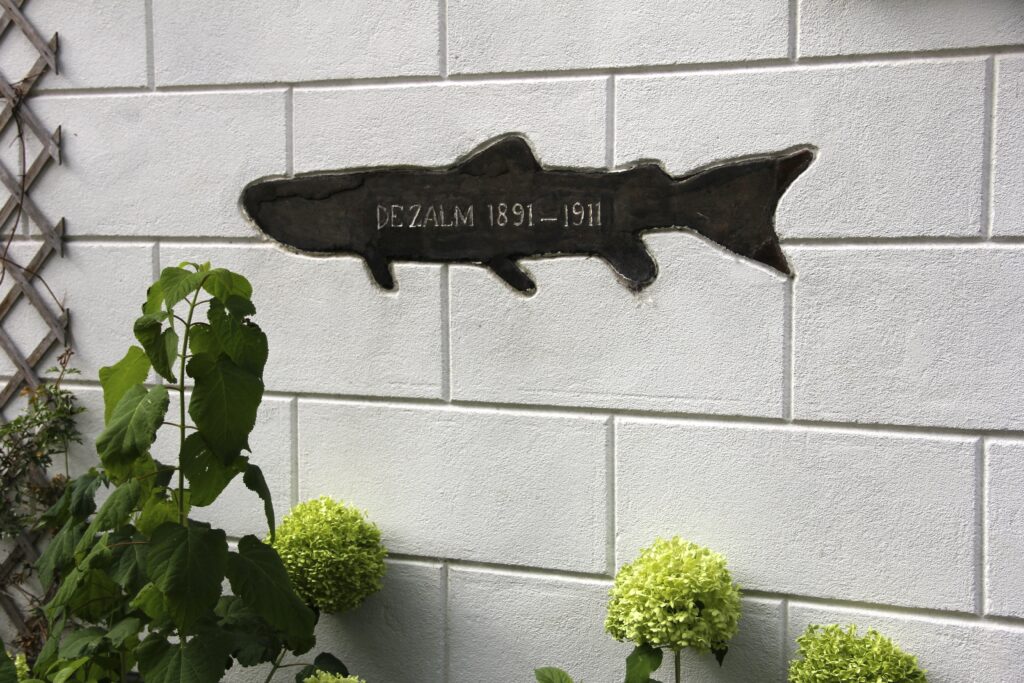 Gemetselde zalm aan de witte gevel met De Zalm 1891-1911